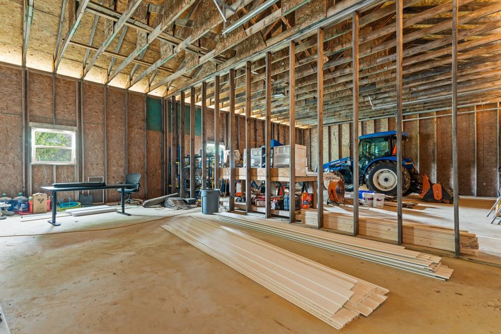 1129 Holly Road Gilmer, TX 75644 - Photo 25 of 31 Spacious interior with exposed wood beam ceiling, concrete flooring, window with natural light, and structural wood framing