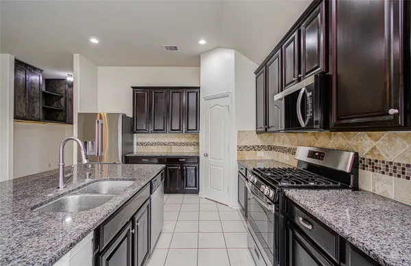 a kitchen with stainless steel appliances granite countertop a sink stove microwave and refrigerator