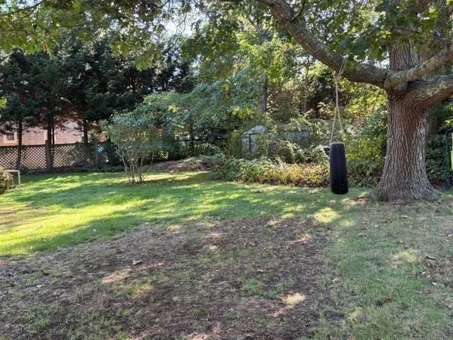 a view of a wooden house with a big yard and large trees