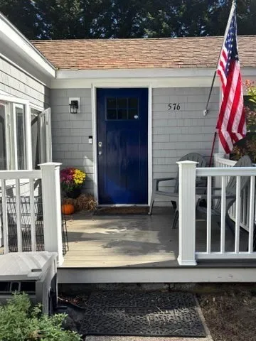 a view of a house with a small yard and wooden floor and fence