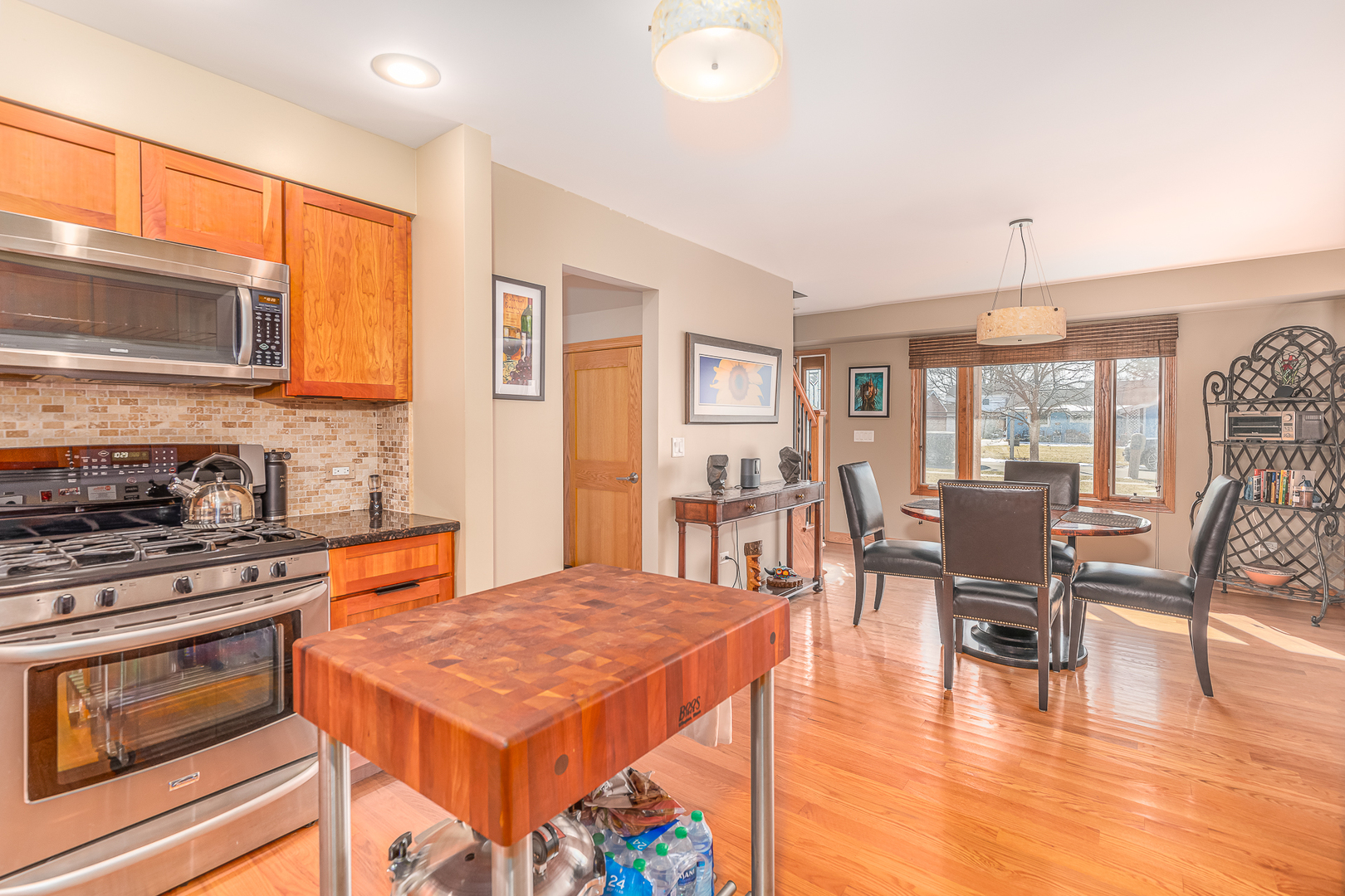 181 Queenswood Road Bolingbrook, IL 60440 - Photo 12 of 46 a open kitchen with stainless steel appliances granite countertop a stove top oven a dining table and chairs with wooden floor