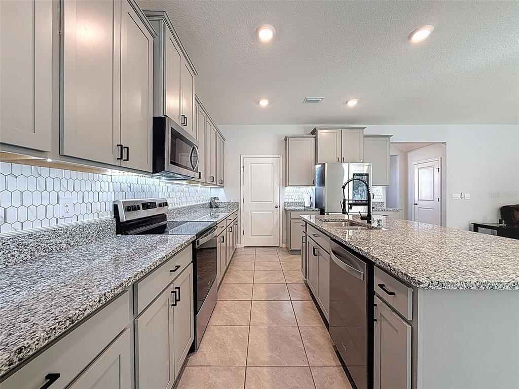 3797 Autumn Amber Dr Spring Hill Spring Hill, FL 34609 - Photo 12 of 44 a large kitchen with stainless steel appliances granite countertop a sink stove and cabinets