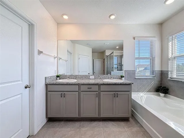 a bathroom with a granite countertop sink a mirror a bathtub and shower