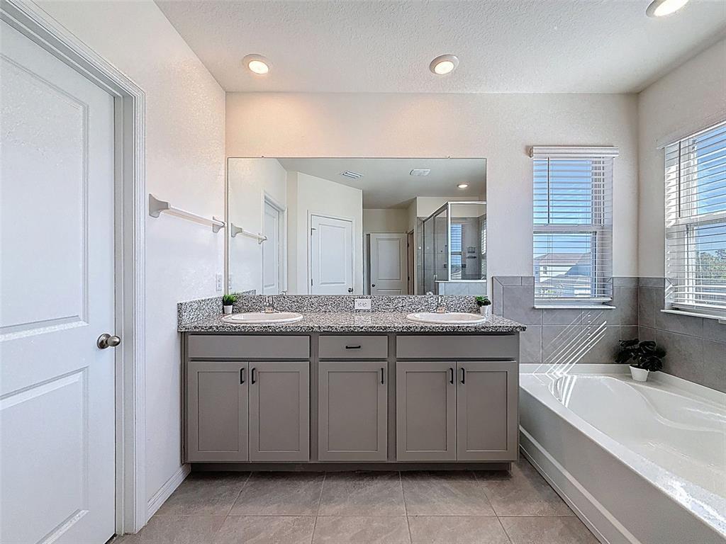 3797 Autumn Amber Dr Spring Hill Spring Hill, FL 34609 - Photo 25 of 44 a bathroom with a granite countertop sink a large mirror a bathtub and a shower