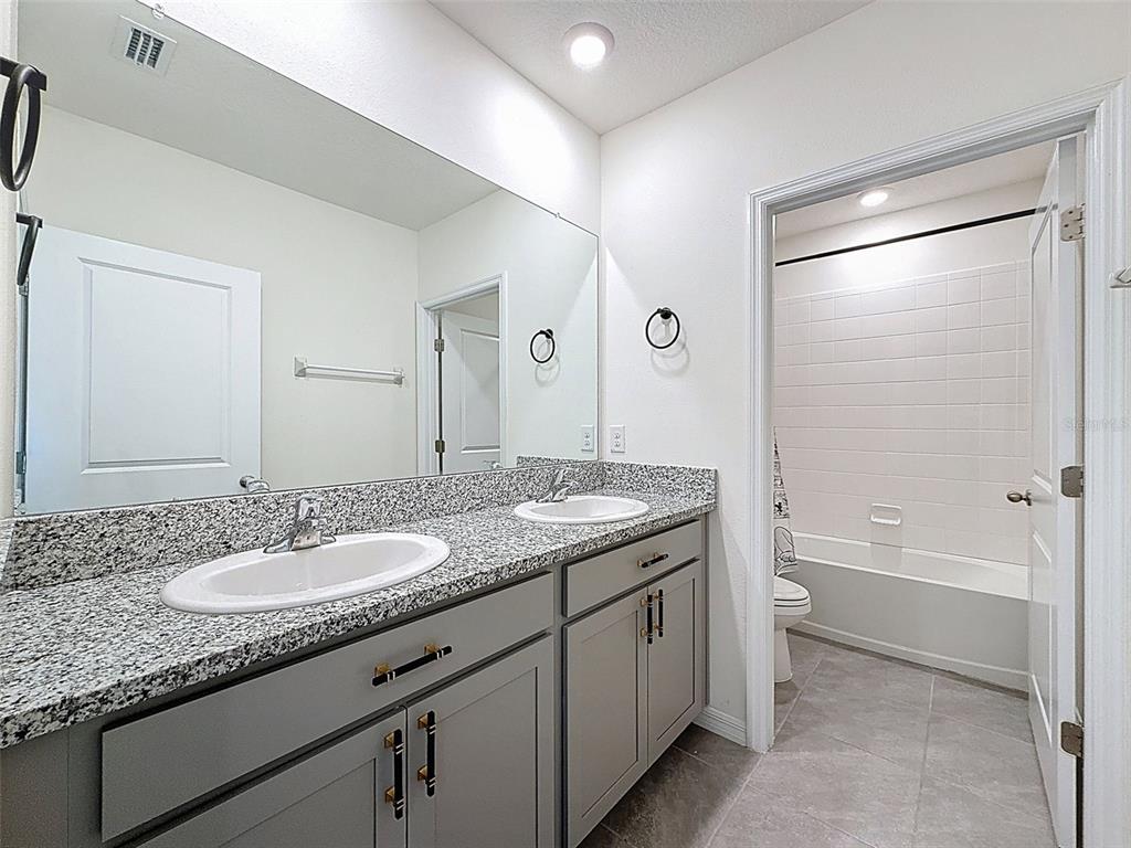 3797 Autumn Amber Dr Spring Hill Spring Hill, FL 34609 - Photo 26 of 44 a bathroom with a granite countertop sink a mirror a bathtub and shower