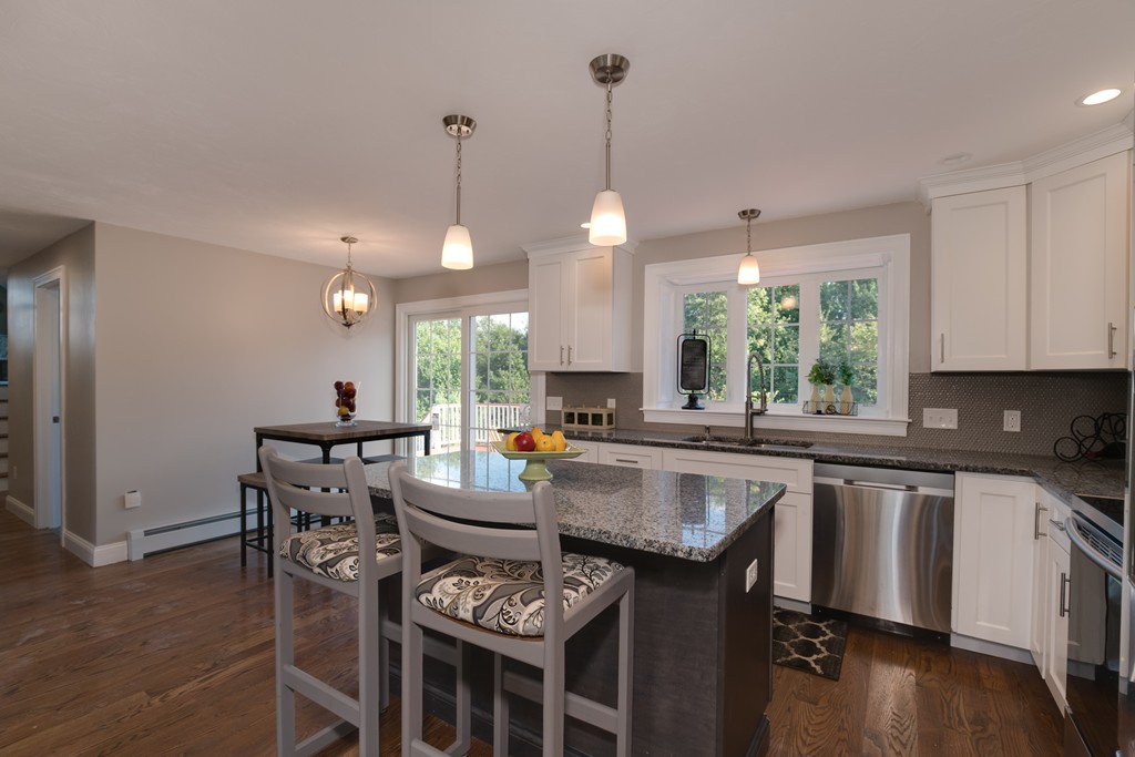 15 Winifreds Way Rutland, MA 01543 - Photo 6 of 30 a kitchen with stainless steel appliances granite countertop a stove a sink a microwave a dining table and chairs with wooden floor