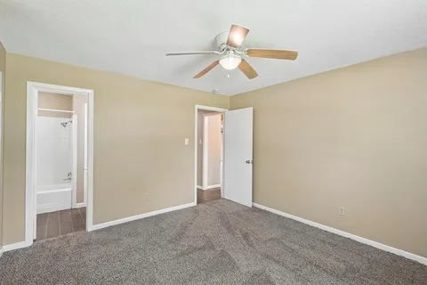 a view of an empty room and chandelier fan