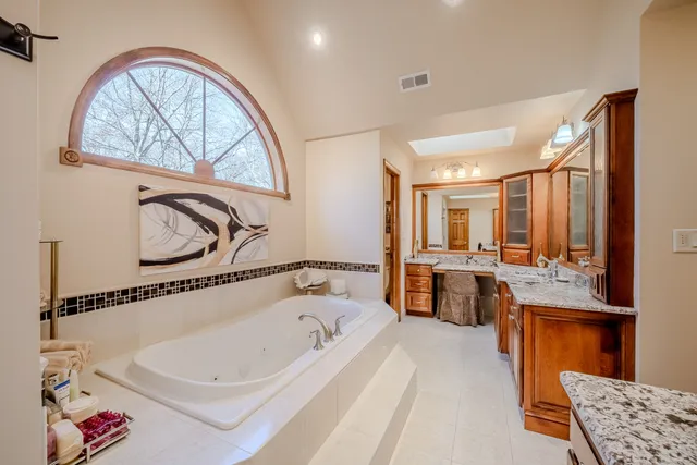 a view of spacious bathroom with a tub and mirror