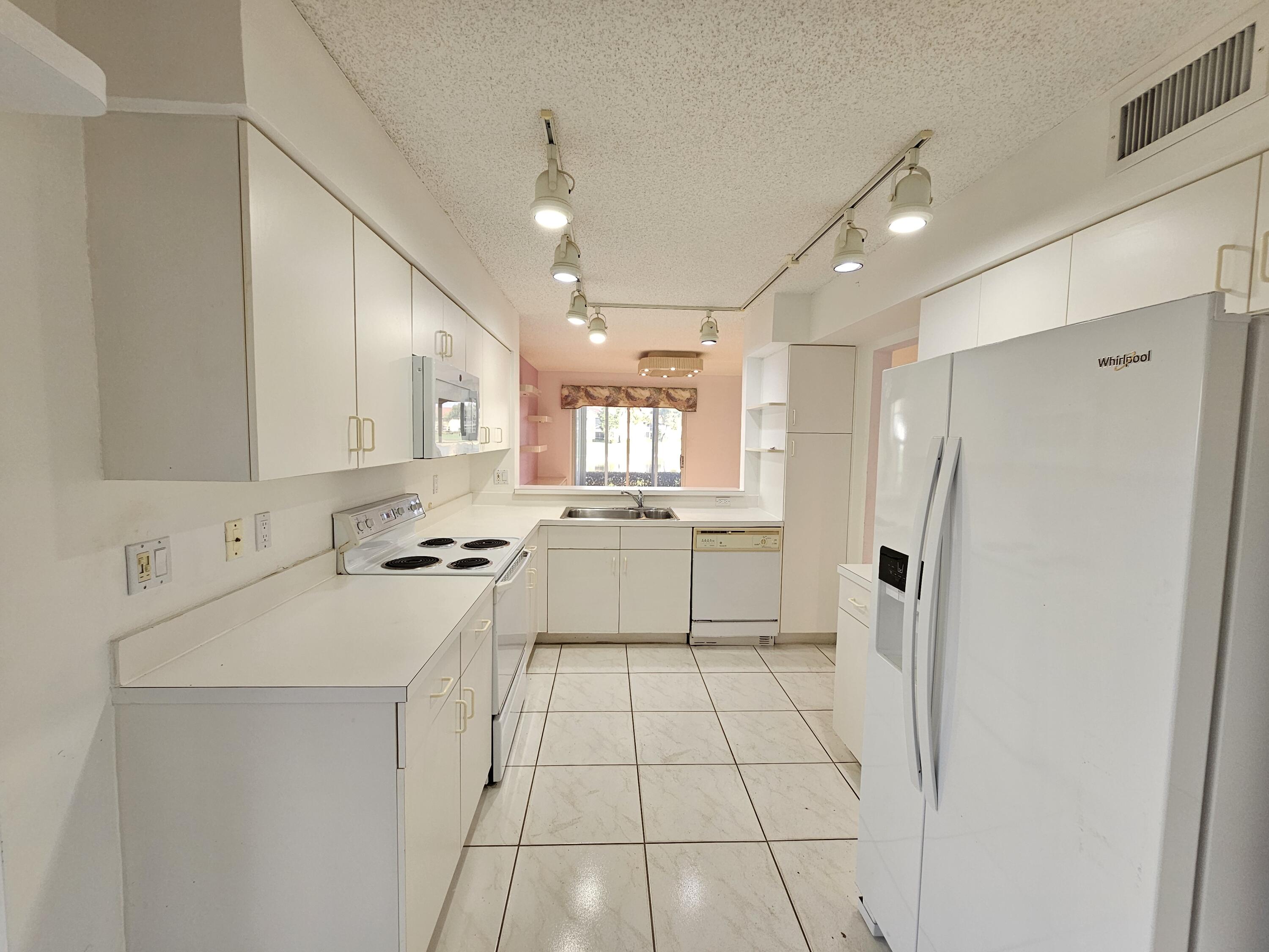 9963 Seacrest Circle, Unit 101 Boynton Beach, FL 33437 - Photo 10 of 27 a kitchen with white cabinets and white appliances