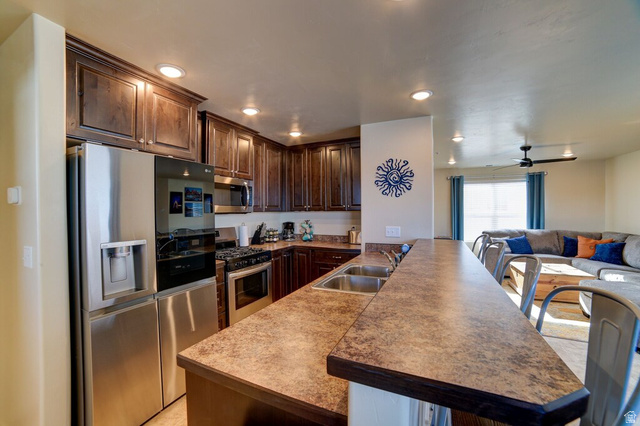 3853 South Red Valley Circle, Unit 22A1 Moab, UT 84532 - Photo 28 of 28 Kitchen with a kitchen bar, stainless steel appliances, a peninsula, dark wood finish cabinetry, and open floor plan