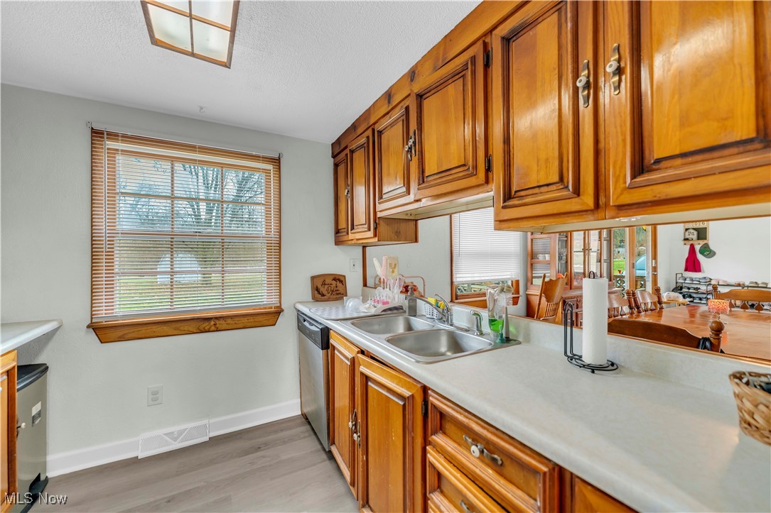 14808 Darrow Road Vermilion, OH 44089 - Photo 17 of 45 Kitchen featuring stainless steel dishwasher, sink, a textured ceiling, and light wood-type flooring