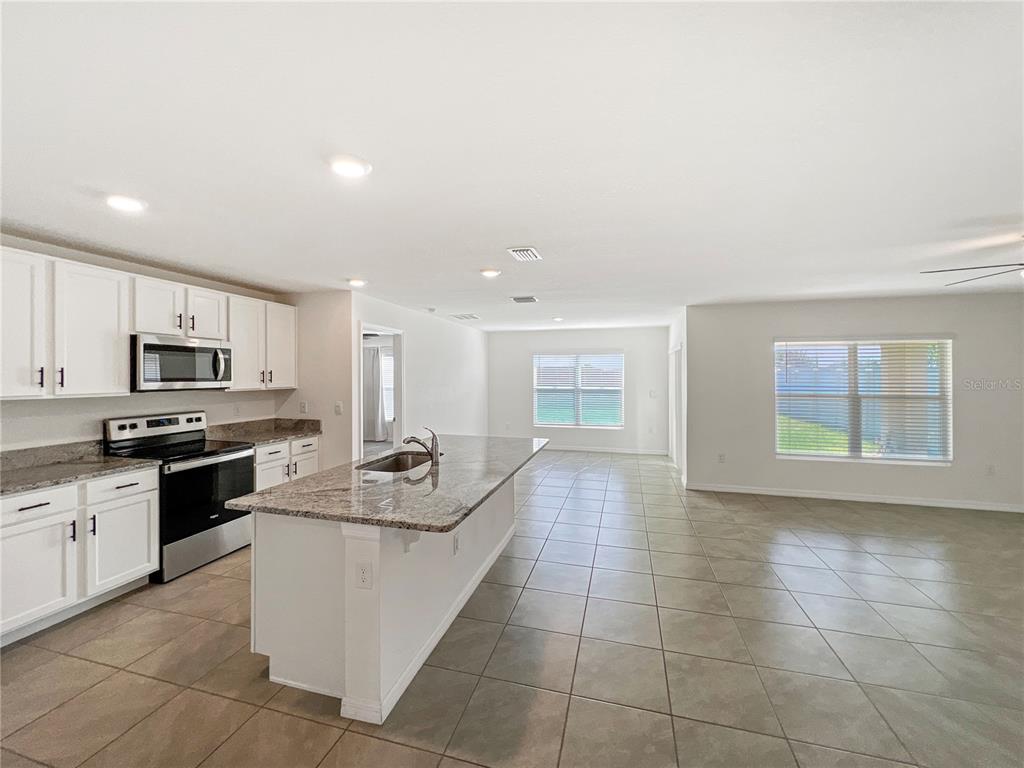5563 Southwest 43rd Court Ocala, FL 34474 - Photo 13 of 51 a kitchen with stainless steel appliances granite countertop a sink stove and microwave