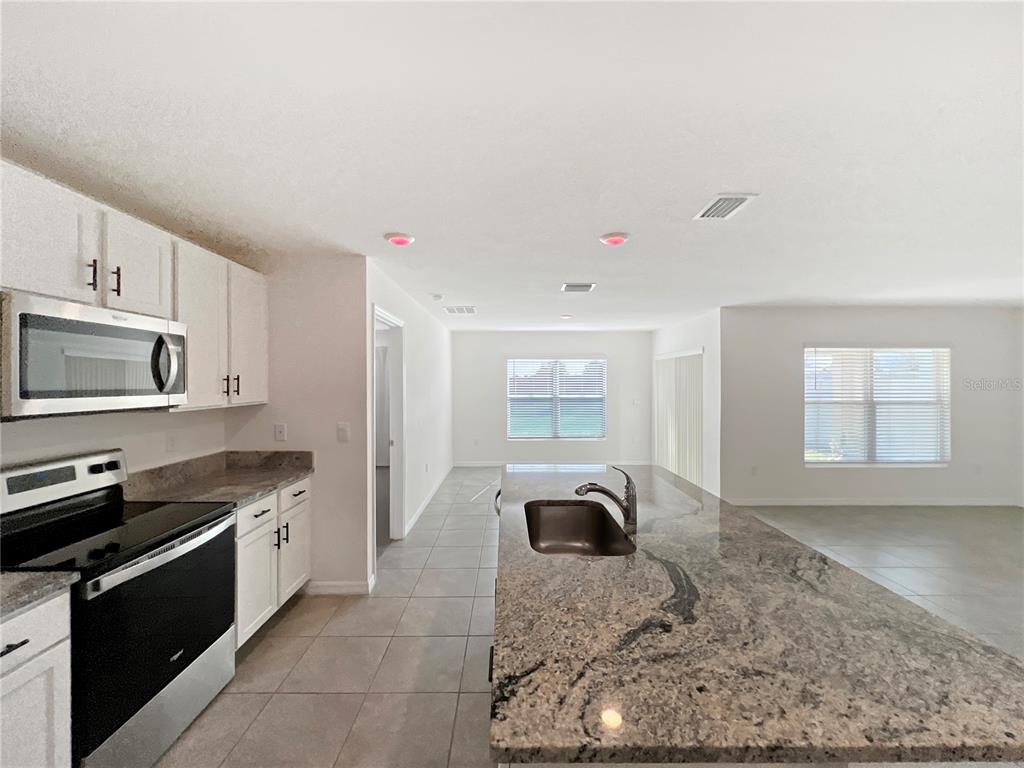 5563 Southwest 43rd Court Ocala, FL 34474 - Photo 16 of 51 a kitchen with granite countertop a sink and a stove top oven