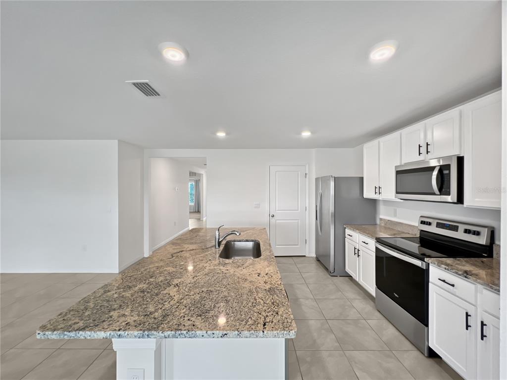 5563 Southwest 43rd Court Ocala, FL 34474 - Photo 17 of 51 a kitchen with stainless steel appliances granite countertop a sink and stove top oven with wooden floor
