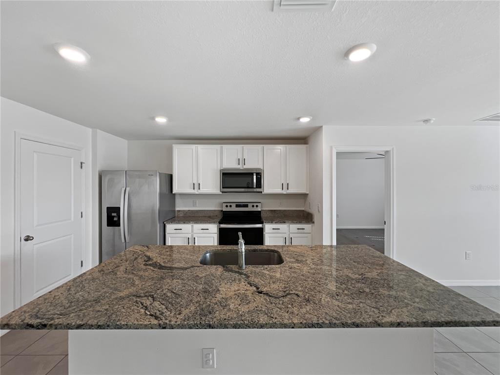 5563 Southwest 43rd Court Ocala, FL 34474 - Photo 18 of 51 a kitchen with stainless steel appliances granite countertop a sink stove and refrigerator