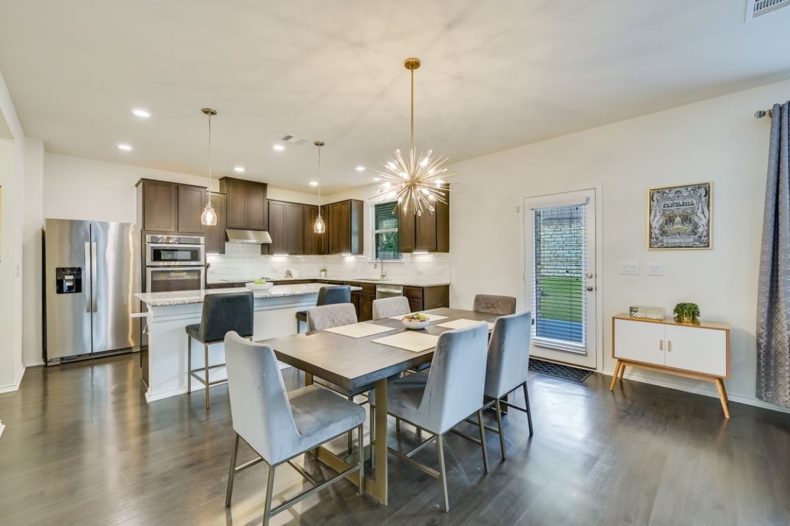 a dining room with kitchen island stainless steel appliances furniture a dining table and chairs