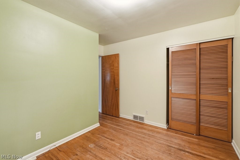 161 Pinehurst Road Munroe Falls, OH 44262 - Photo 20 of 40 Room featuring wood-finish flooring, a louvered bi-fold closet, a solid wood door, white baseboards, and a ceiling-mounted light fixture