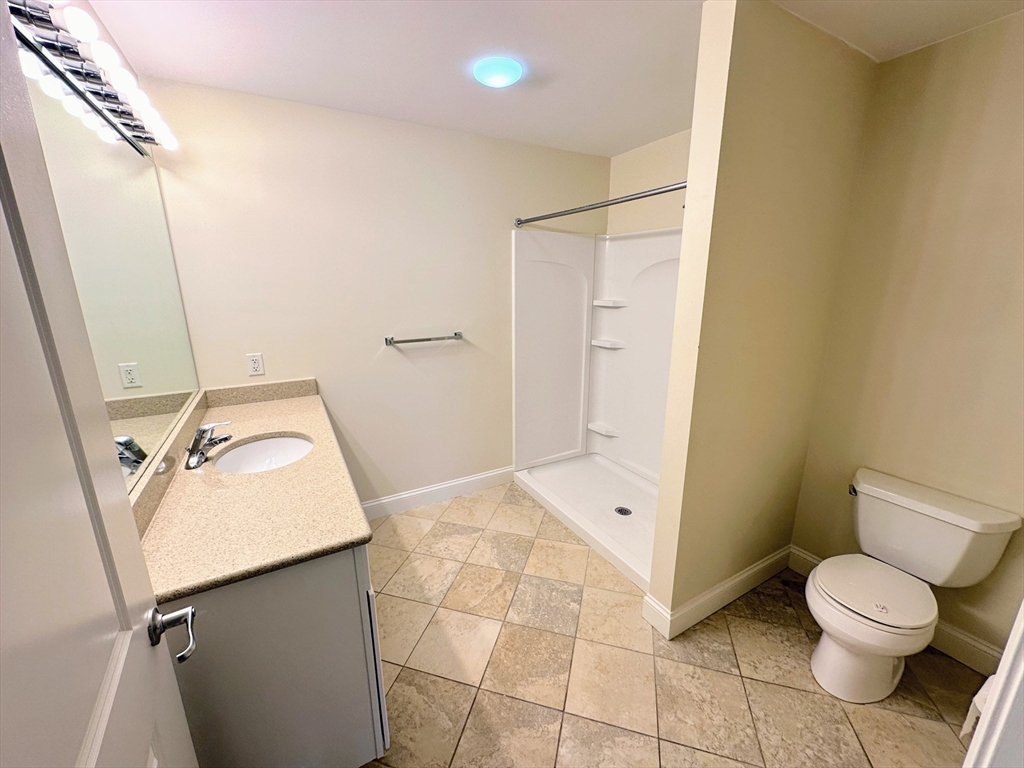 318 Rindge Avenue, Unit 216 Cambridge, MA 02140 - Photo 10 of 15 a bathroom with a toilet sink and mirror