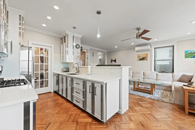 a kitchen with stainless steel appliances kitchen island granite countertop a refrigerator a stove a sink dishwasher and white cabinets with wooden floor