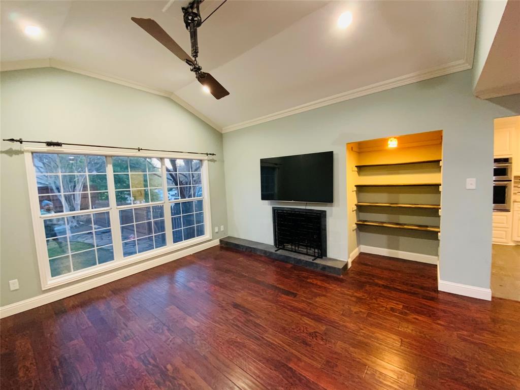 4902 West Mockingbird Lane Dallas, TX 75209 - Photo 4 of 7 a view of a livingroom with wooden floor a ceiling fan a fireplace and windows