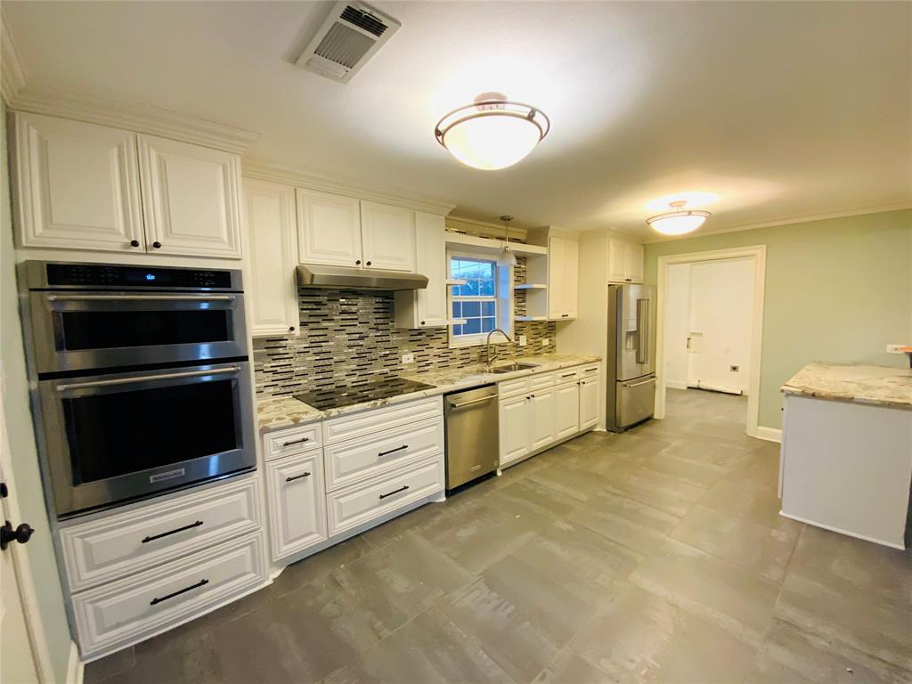 4902 West Mockingbird Lane Dallas, TX 75209 - Photo 6 of 7 a kitchen with granite countertop white cabinets and stainless steel appliances