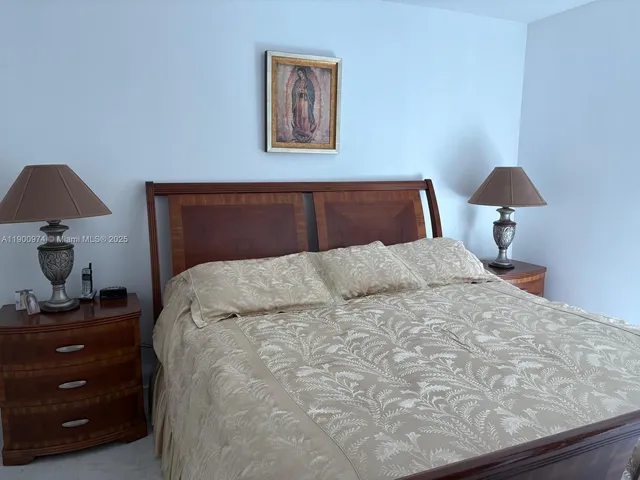a bedroom with a bed and a lamp on dresser