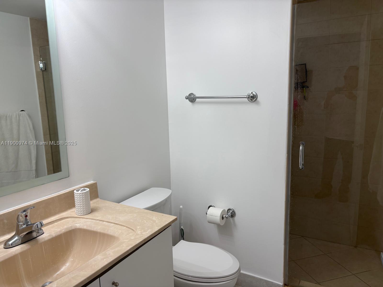 9055 Southwest 73rd Court, Unit 1806 Miami, FL 33156 - Photo 18 of 23 a bathroom with a granite countertop sink toilet and a mirror