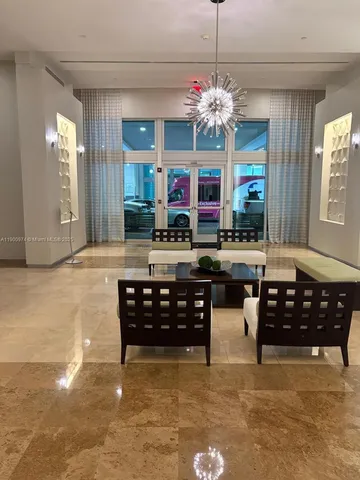 a living room with furniture a chandelier and kitchen view