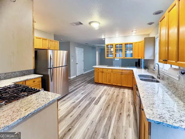 a view of kitchen with stainless steel appliances granite countertop sink stove refrigerator and cabinets