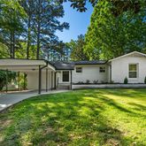 a view of a house with a yard and a large tree