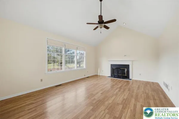a view of empty room with wooden floor fan and window