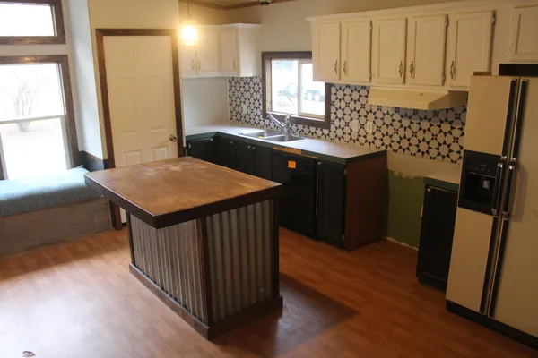 a kitchen with a sink a refrigerator and wooden cabinets