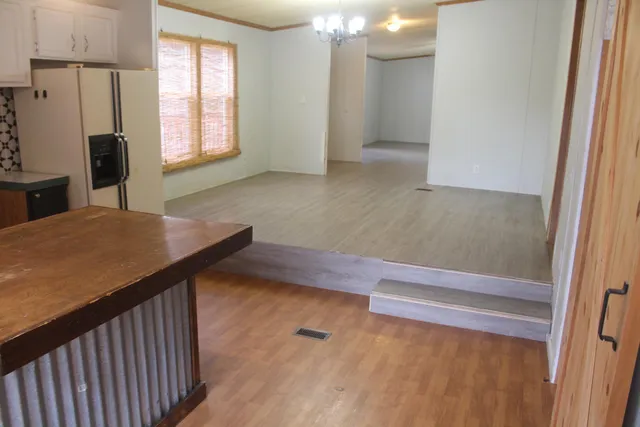 a view of an empty room with wooden floor and a fireplace