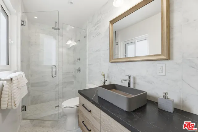 a bathroom with a granite countertop sink a toilet and shower