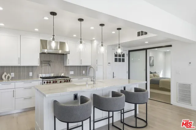 a kitchen with stainless steel appliances kitchen island granite countertop a sink a stove a refrigerator and chairs