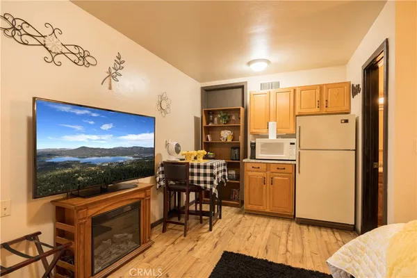 a kitchen with stainless steel appliances kitchen island granite countertop a refrigerator a stove a microwave oven with a dining table and chairs with wooden floor