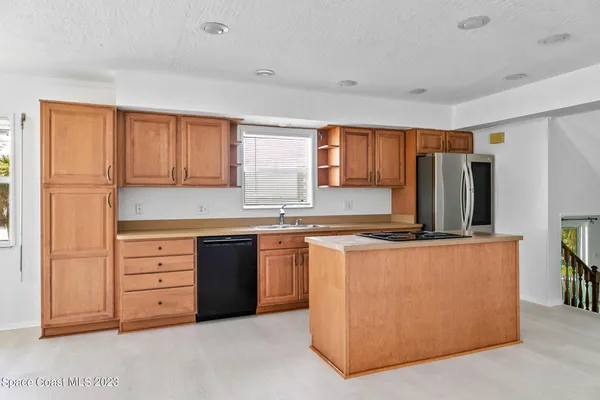 a kitchen with stainless steel appliances granite countertop a refrigerator a stove a sink and a refrigerator with wooden cabinets