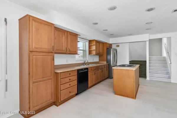 a kitchen with granite countertop a refrigerator a sink and dishwasher