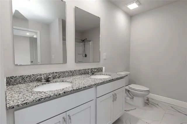 a bathroom with a granite countertop sink a toilet and a mirror