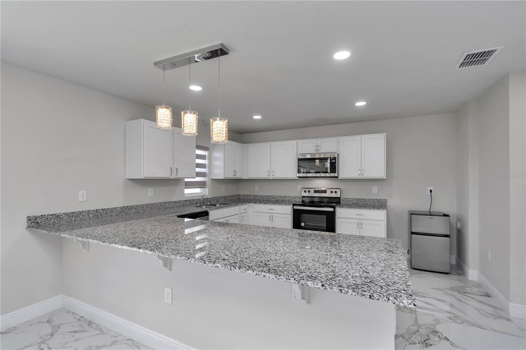 10090 Southeast 67th Terrace Belleview, FL 34420 - Photo 37 of 40 a kitchen with stainless steel appliances granite countertop a sink stove and cabinets