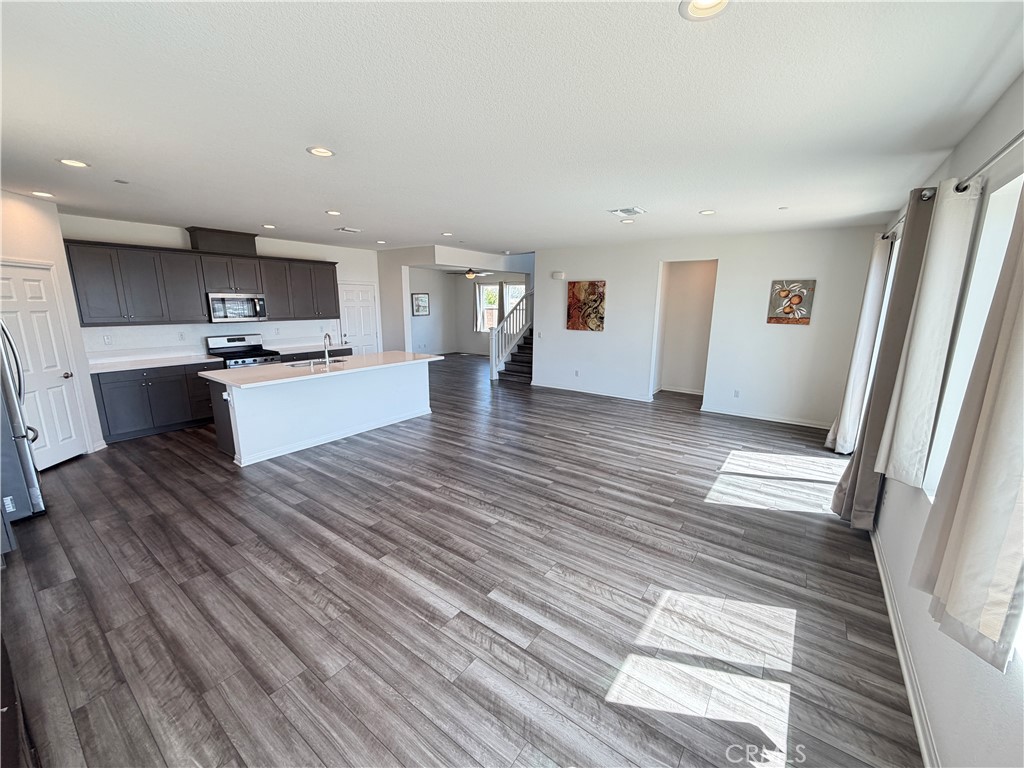 7483 Sage Scrub Road Riverside, CA 92507 - Photo 5 of 33 an empty room with wooden floor and a kitchen