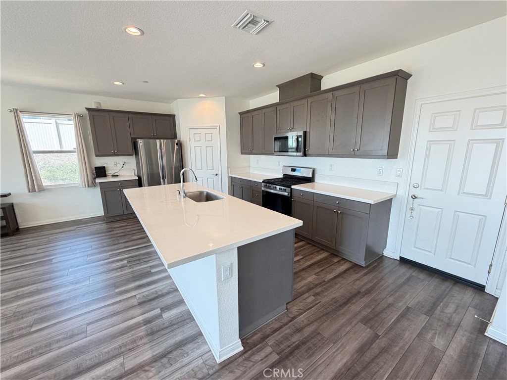 7483 Sage Scrub Road Riverside, CA 92507 - Photo 7 of 33 a large kitchen with kitchen island a sink a center island stainless steel appliances and a window