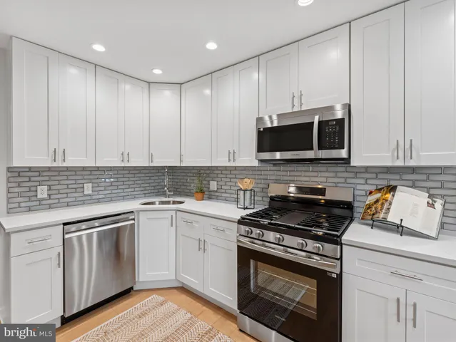 a kitchen with cabinets stainless steel appliances and wooden floor