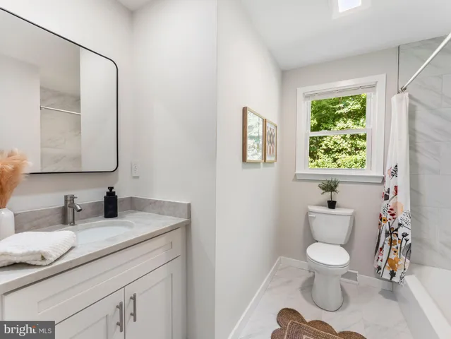 a bathroom with a granite countertop toilet sink and mirror