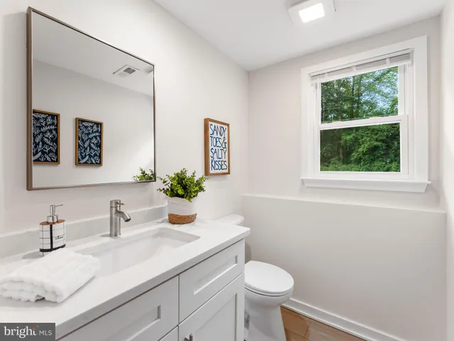 a bathroom with a granite countertop sink toilet and a window