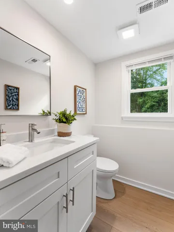 a bathroom with a granite countertop sink mirror and a toilet