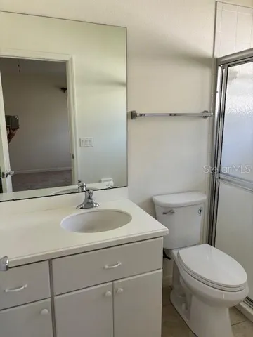a bathroom with a granite countertop toilet sink and mirror