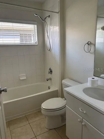 a bathroom with a granite countertop bathtub shower sink vanity and toilet