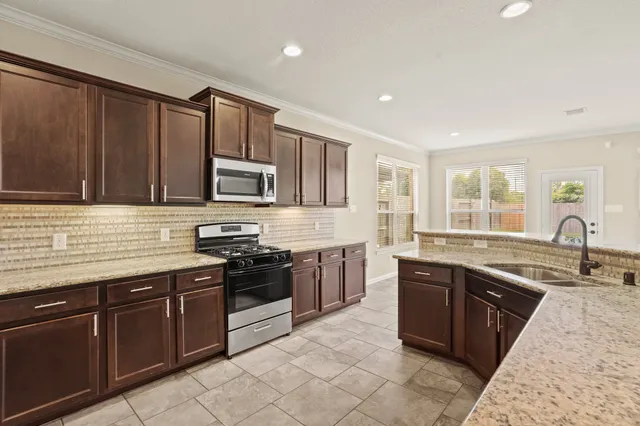 a kitchen with stainless steel appliances granite countertop a sink stove and refrigerator