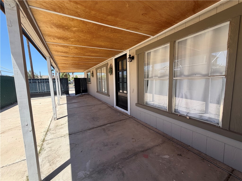 1910 Rio Grande Road Bullhead City, AZ 86442 - Photo 24 of 29 Covered patio area featuring a concrete slab, supporting columns, and a wood-panel ceiling